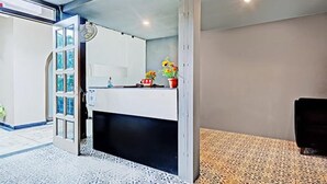 A modern reception area with a glass door entrance, a counter with potted plants, and patterned flooring. - Fabhotel Prime Garden View (Jaipur)