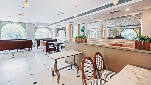 A modern restaurant with high ceilings, pendant lighting, and a mix of seating including tables and benches. - Fabhotel Prime Garden View (Jaipur)