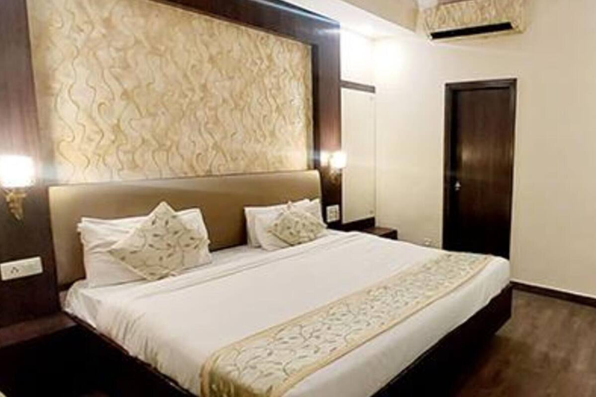 A hotel room with a large bed, a headboard with a textured design, two bedside tables, and a wardrobe.