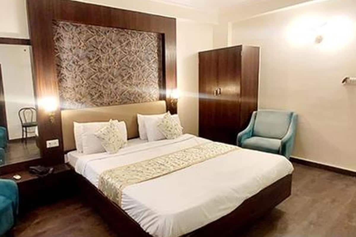 A hotel room with a large bed, two chairs, a wardrobe, and a mirror.