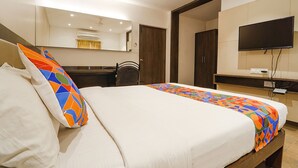 A hotel room with a bed, a TV, a desk, and a mirror. - Fabhotel Karpagam (Coimbatore)