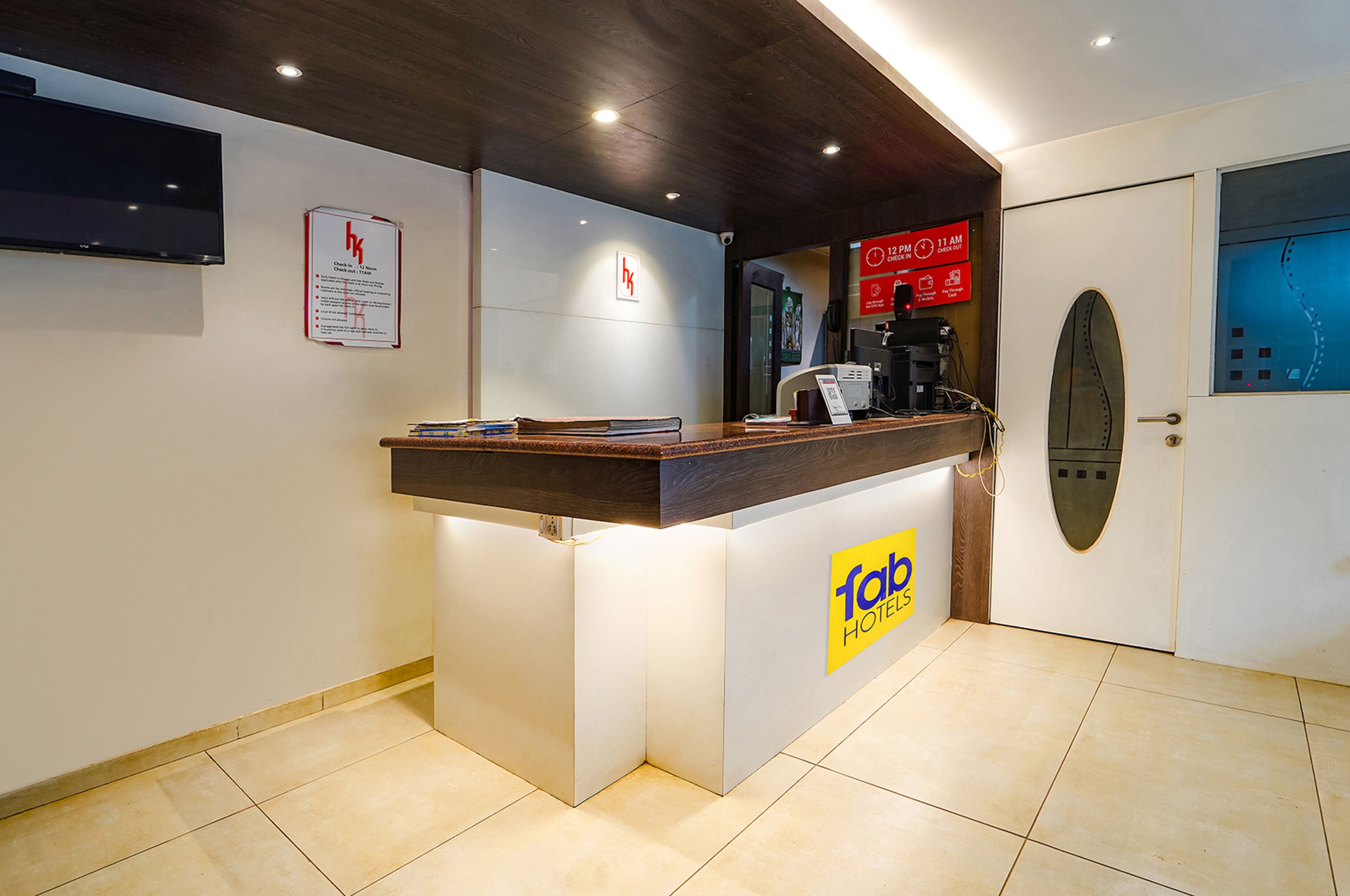 A hotel reception desk with a digital screen, a coffee machine, and a sign for the hotel.