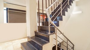 A modern staircase with metal railings and dark steps, leading to an upper floor. - Fabhotel Karpagam (Coimbatore)