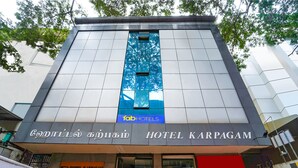 A modern hotel facade with a prominent blue glass section and signage in multiple languages. - Fabhotel Karpagam (Coimbatore)
