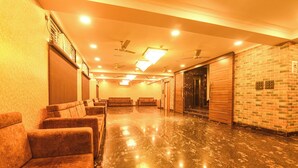 A hotel lobby with a marble floor, sofas, a brick wall, and ceiling fans. - Fabhotel Prime Tiyara Inn (Barasat)