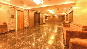 A hotel lobby with marble flooring, wooden walls, and ceiling fans. - Fabhotel Prime Tiyara Inn (Barasat)