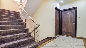 Eine Treppe mit Metallgeländer, die zu einer Zwischenebene führt, mit einer Holztür und einem Fliesenboden.