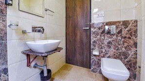 Ein Badezimmer mit einem weißen Waschbecken, einer Holztür und einer Toilette.