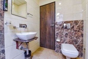 Un baño con un lavamanos blanco, una puerta de madera y un inodoro.