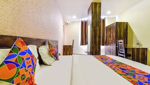 Ein Hotelzimmer mit einem Bett, einem Schreibtisch, einem Stuhl, einem Kleiderschrank und einem Spiegel.