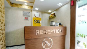 A reception desk with a wooden finish, a clock, and a sign indicating 'fab hotels' and 'no drugs' policy. - Fabhotel Fortuna Inn (Navi Mumbai)