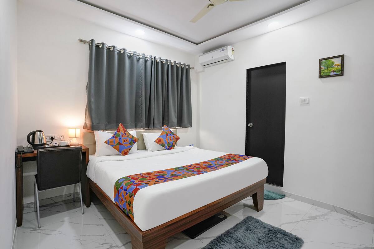 Une chambre d’hôtel avec un lit, un bureau, une chaise et une porte.