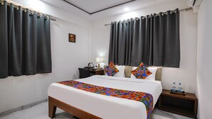 A hotel room with a large bed, two bedside tables, a nightstand, a desk with a lamp, and a picture on the wall. - Fabhotel Fortuna Inn (Navi Mumbai)