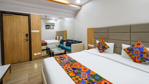 A modern hotel room with a large bed, a sofa, a desk, and a small table. - FabHotel Aditya Homes (Hyderabad)