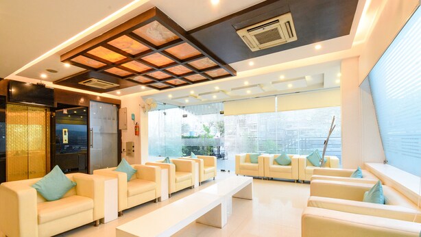 A modern hotel lobby with a reception desk, seating area, and large windows. - FabHotel Aditya Homes (Hyderabad)