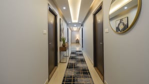 A modern hallway with a tiled floor, a round mirror, and framed artwork on the walls. - FabHotel Aditya Homes (Hyderabad)