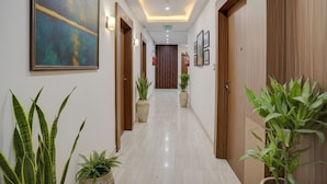 A hotel hallway with a modern design, featuring a long corridor with wooden doors, potted plants, and framed artwork on the walls. - FabHotel The Sky - Nr. Calangute Beach (Calangute)