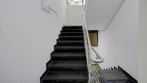 A staircase with black steps and a metal handrail, leading to a landing with a window. - FabHotel The Sky - Nr. Calangute Beach (Calangute)