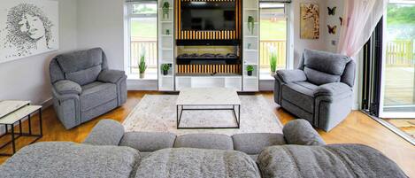 A modern living room with grey sofas, a central coffee table, and a TV mounted on a wall.
