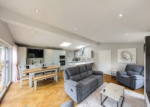 A modern apartment with a dining area, kitchen, living room, and a large window.