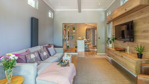 A modern living room with a sofa, coffee table, and a TV mounted on a wooden wall. - The Watchtower (Pet) (Snowdonia)