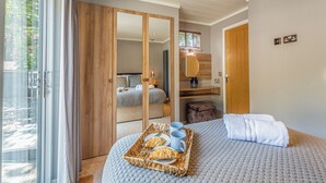A bedroom with a large bed, a wooden wardrobe, a bathroom with a mirror, and a breakfast tray on the bed. - The Watchtower (Pet) (Snowdonia)