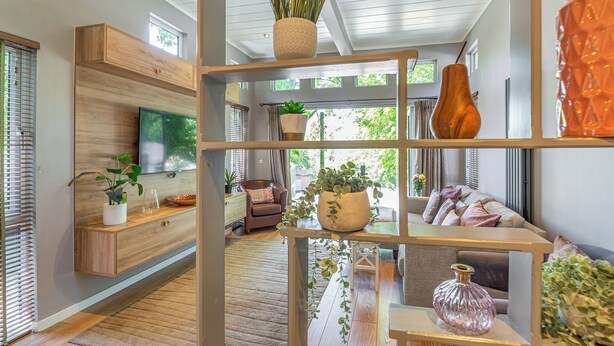 A modern living room with a wooden floor, built-in TV, and a variety of plants and decorative items on shelves. - The Watchtower (Pet) (Snowdonia)