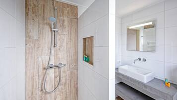 Une salle de bain moderne avec une cabine de douche en bois, un lavabo intégré et un miroir au-dessus du lavabo.