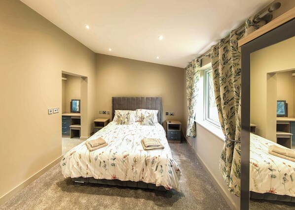 A bedroom with a bed, bedside tables, a TV, and a window with curtains. - Superb bespoke lodge with two bedrooms sleeping up to four people. (Laceby)