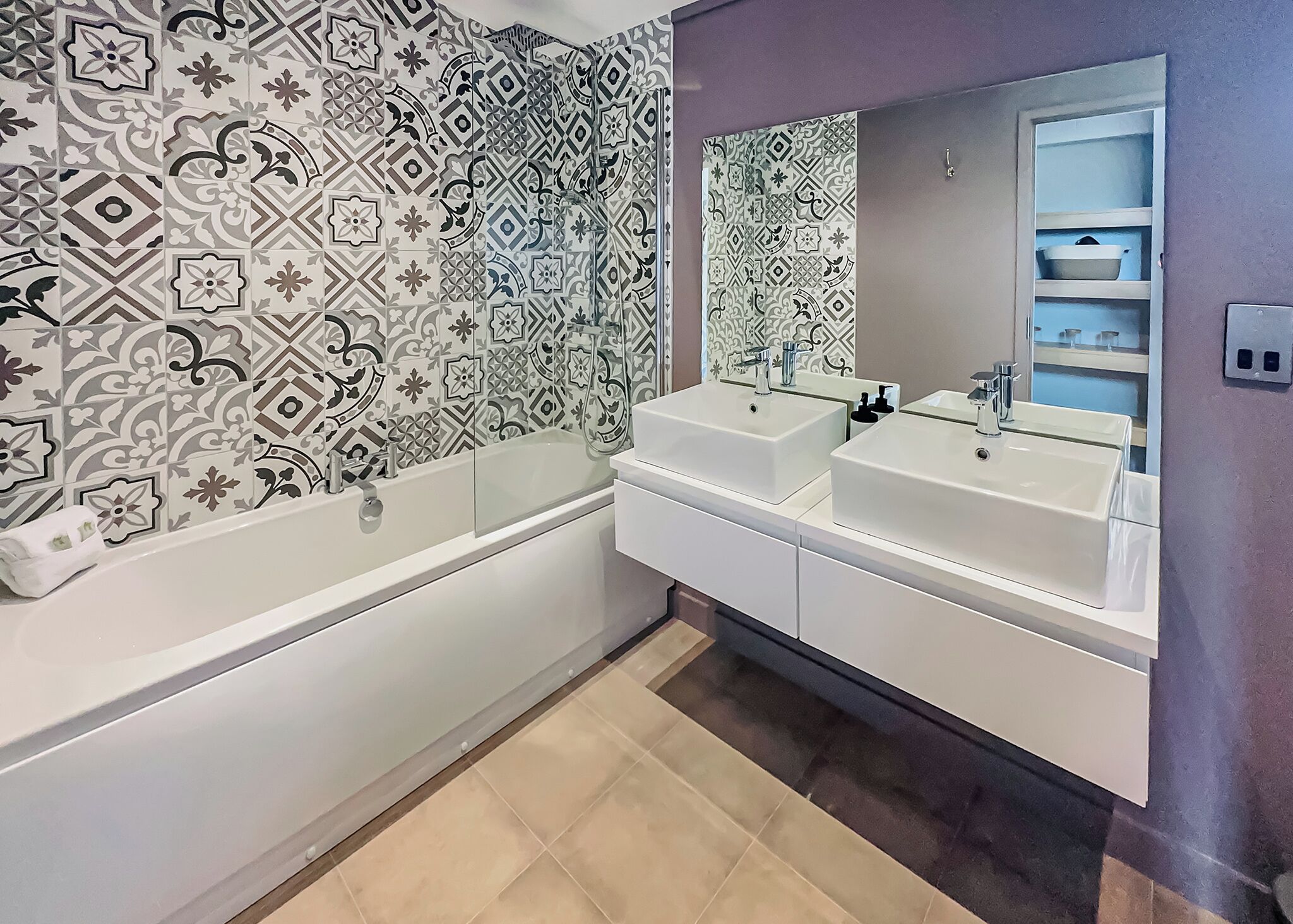 Une salle de bain moderne avec deux lavabos, une baignoire et des carreaux décoratifs sur les murs.