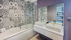 Une salle de bain moderne avec deux lavabos, une baignoire et des carreaux décoratifs sur les murs.