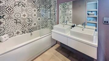 Une salle de bain moderne avec deux lavabos, une baignoire et des carreaux décoratifs sur les murs.