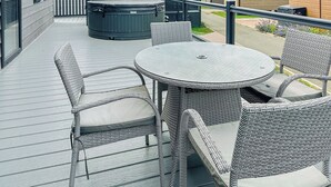 Un espacio al aire libre techado con mobiliario de mimbre, un jacuzzi y vistas de los edificios circundantes.