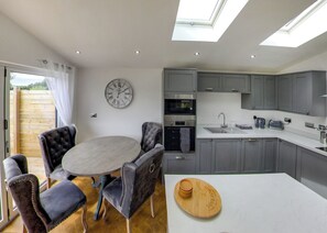 A modern kitchen with grey cabinets, a round dining table, and a clock on the wall.
