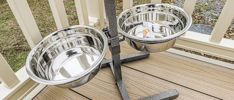 A metal dog bowl stand on a wooden deck.