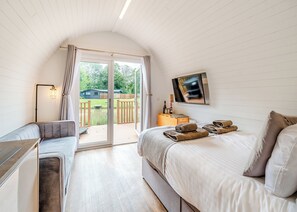 Une chambre avec un lit, un canapé, une télévision et une porte coulissante donnant sur une terrasse.