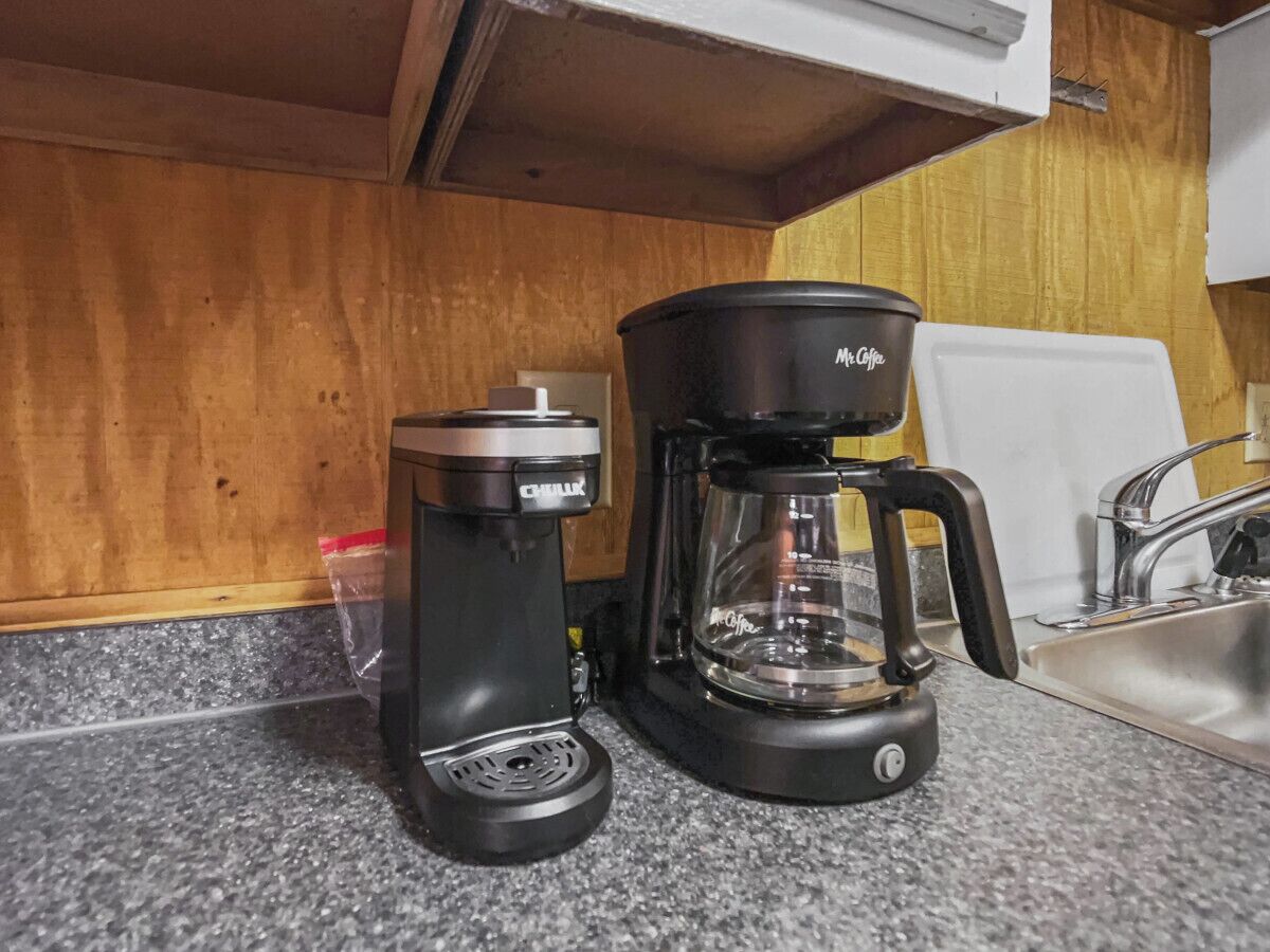 A kitchen with a coffee maker and a coffee pot on the counter.