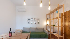 A room with a wooden table, a sofa, a shelving unit, and framed pictures on the wall.