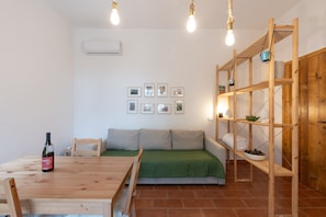 Une pièce avec une table en bois, un canapé, une étagère et des tableaux encadrés accrochés au mur.