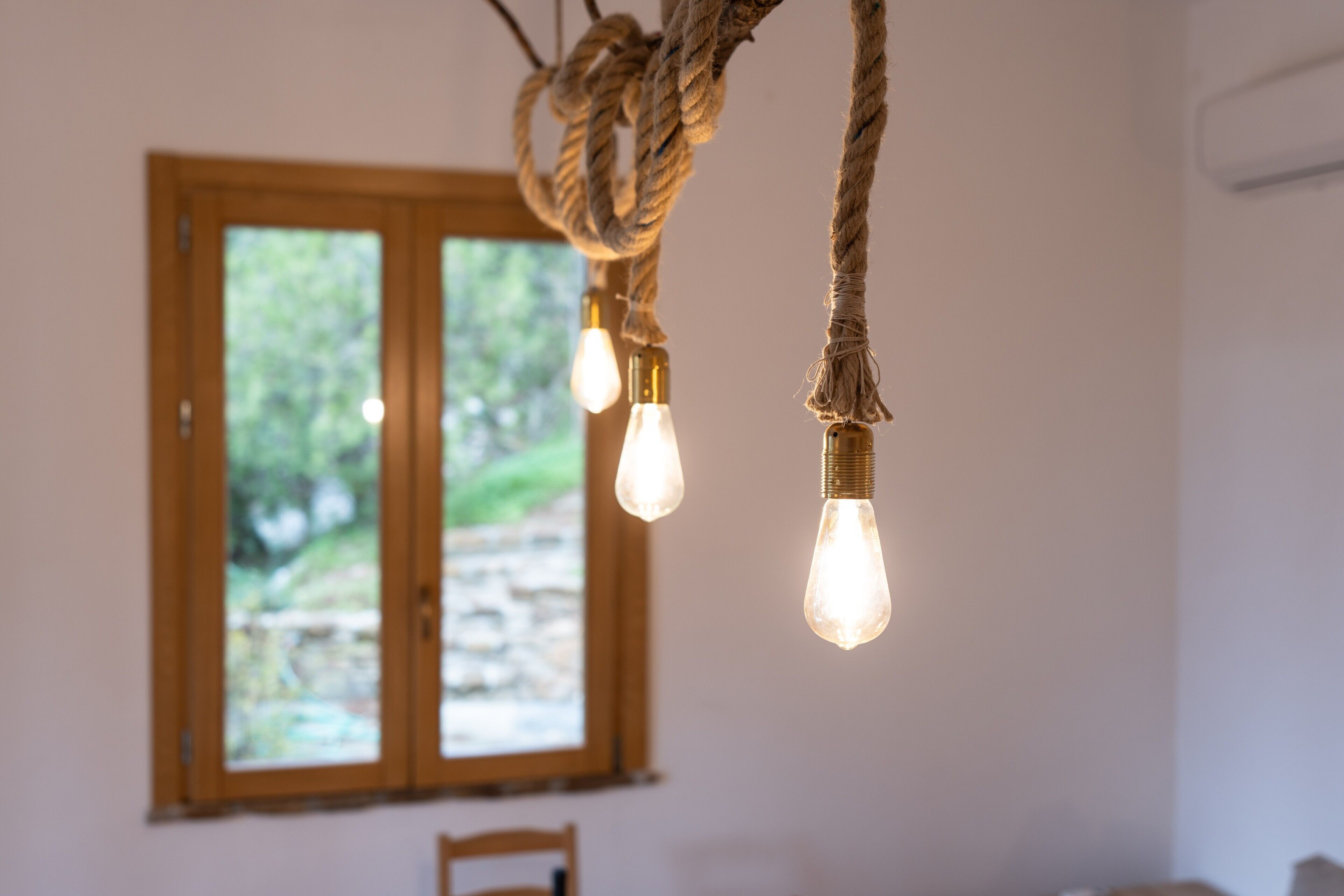 Ein Zimmer mit einem fensterartigen Holzrahmen, einer Lichterkette und einem Sessel.