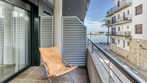 Un balcon avec une seule chaise, une vue sur la mer et un immeuble doté de balcons.