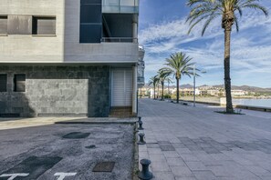 A modern building with a stone facade, a paved walkway, and palm trees.