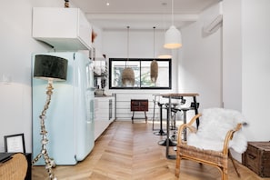 Une cuisine moderne avec un réfrigérateur bleu clair, un plancher en bois et une grande fenêtre donnant sur un beau paysage.