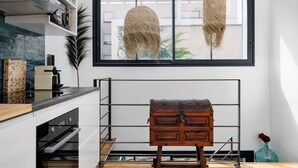 Une cuisine avec une fenêtre, un luminaire suspendu et une commode en bois.
