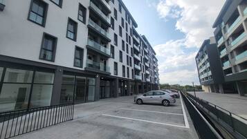 Un immeuble moderne à plusieurs étages, avec un espace de stationnement à l’avant.