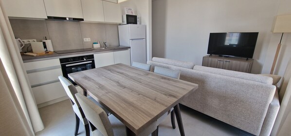 Una cocina moderna con comedor, sofá y televisor.