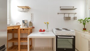 A compact kitchen with a white stove, oven, and wooden table. - Apartment 'Dreaming of Greece G1' with Private Terrace, Wi-Fi and Air Conditioning (Athens)