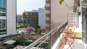 A balcony with a table and chairs, a hanging plant, and a view of buildings. - Apartment 'Dreaming of Greece G1' with Private Terrace, Wi-Fi and Air Conditioning (Athens)
