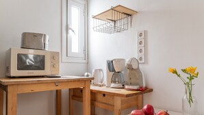 A kitchen with a microwave, coffee maker, and a bowl of fruit on a wooden table. - Apartment 'Dreaming of Greece G1' with Private Terrace, Wi-Fi and Air Conditioning (Athens)