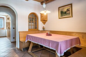 Un coin repas avec un banc et une table en bois, un luminaire suspendu et un tableau encadré au mur.